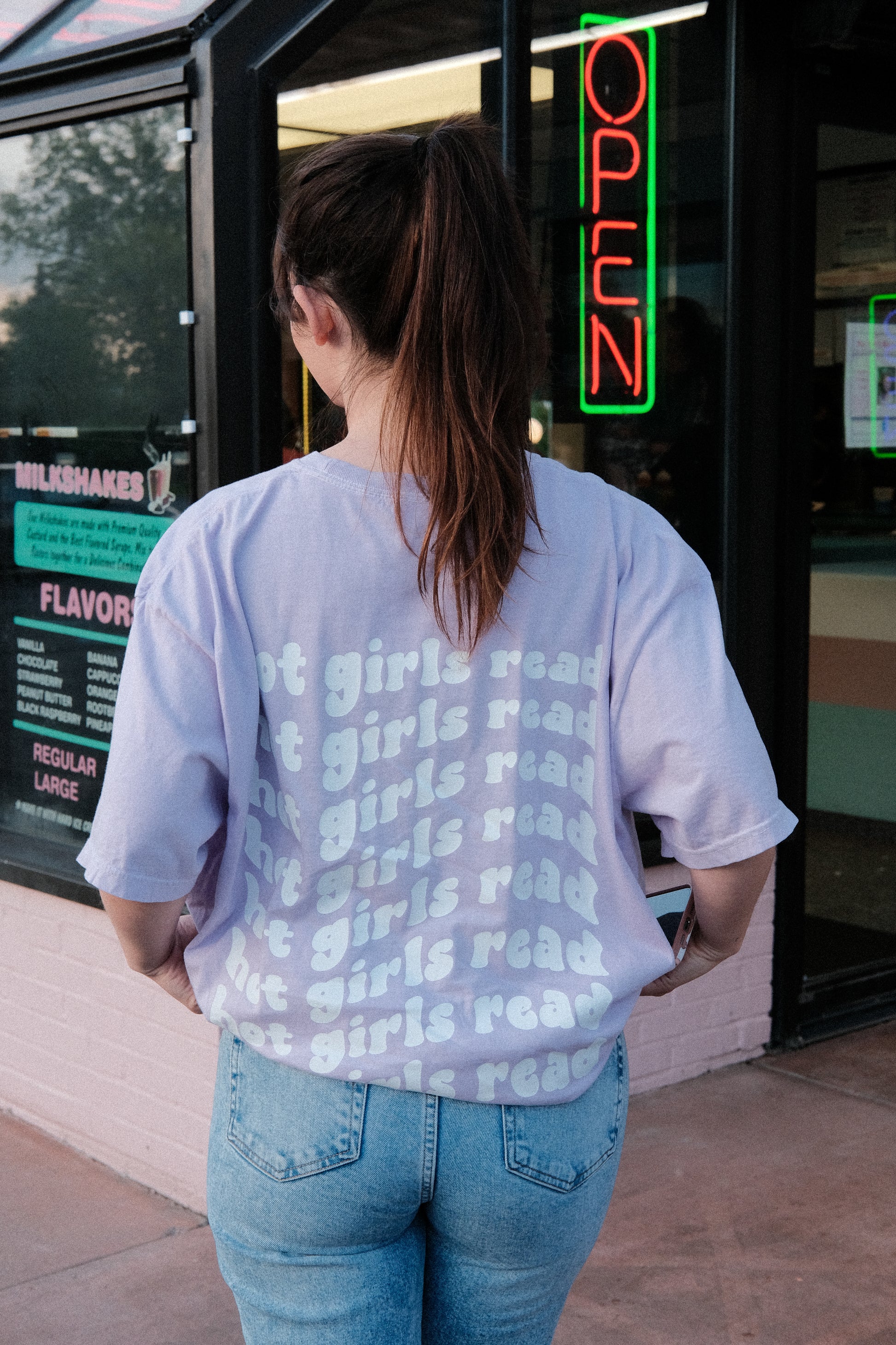 booktuber alexa raye wearing a orchid purple shirt that says hot girls read in trendy aesthetic font