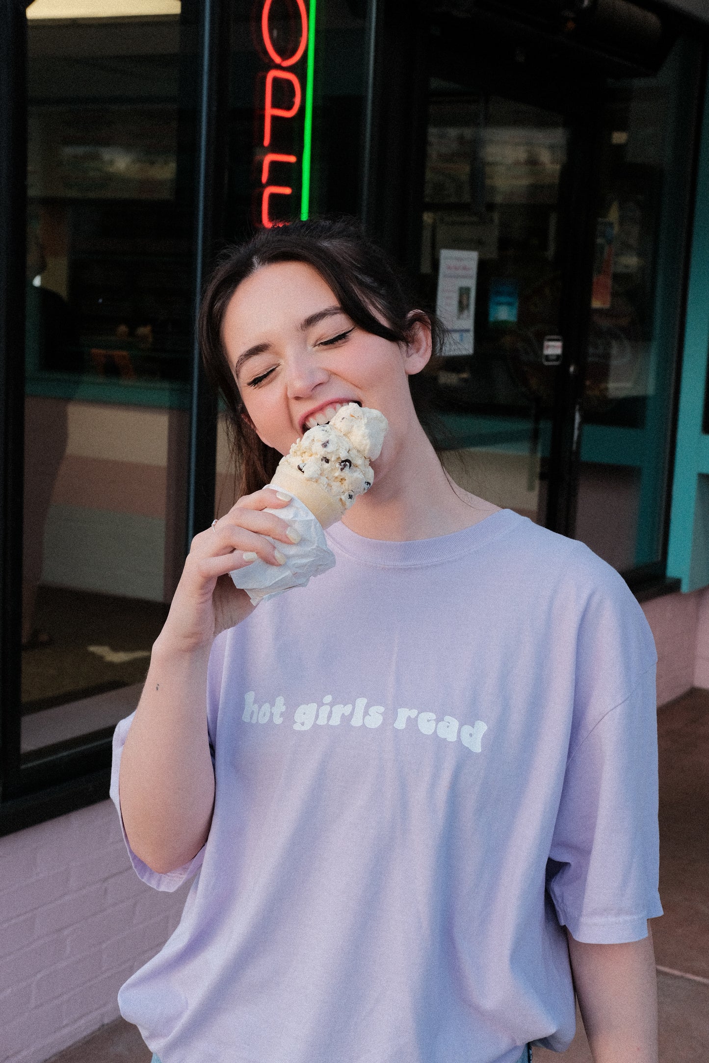 booktuber alexa raye eating ice cream while wearing a orchid purple shirt that says hot girls read in trendy aesthetic font